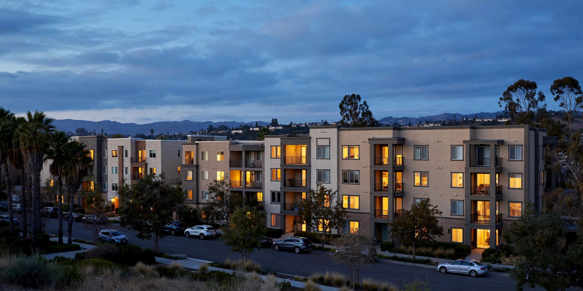 Apartment buildings in San Jose at dusk with lights coming on